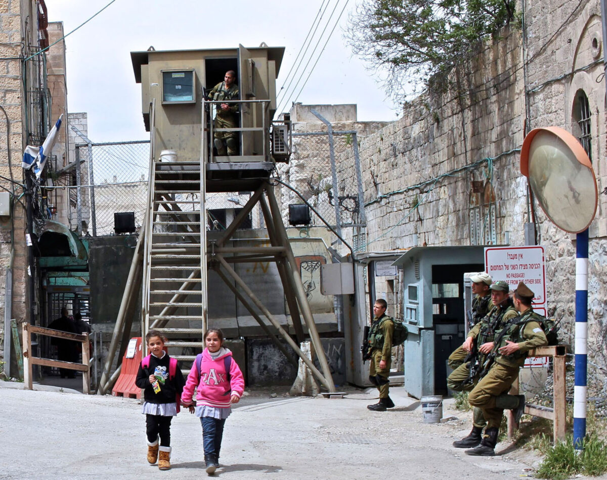 Palestinian children pass a military checkpoint in Hebron to get to school
