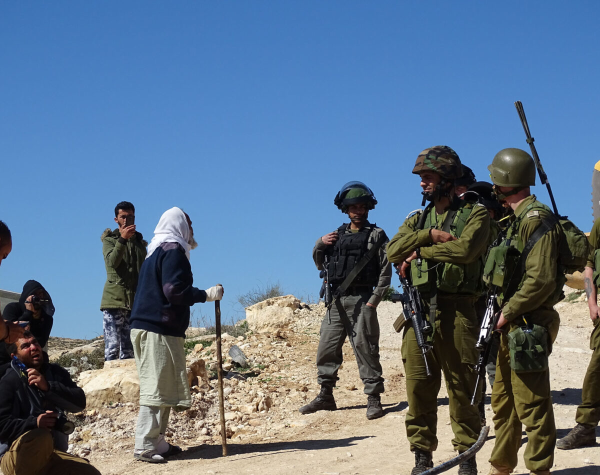 A Palestinian shepherd complains to Israeli soldiers as community water pipes are destroyed