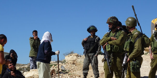 A Palestinian shepherd complains to Israeli soldiers as community water pipes are destroyed
