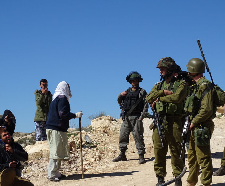 A Palestinian shepherd complains to Israeli soldiers as community water pipes are destroyed