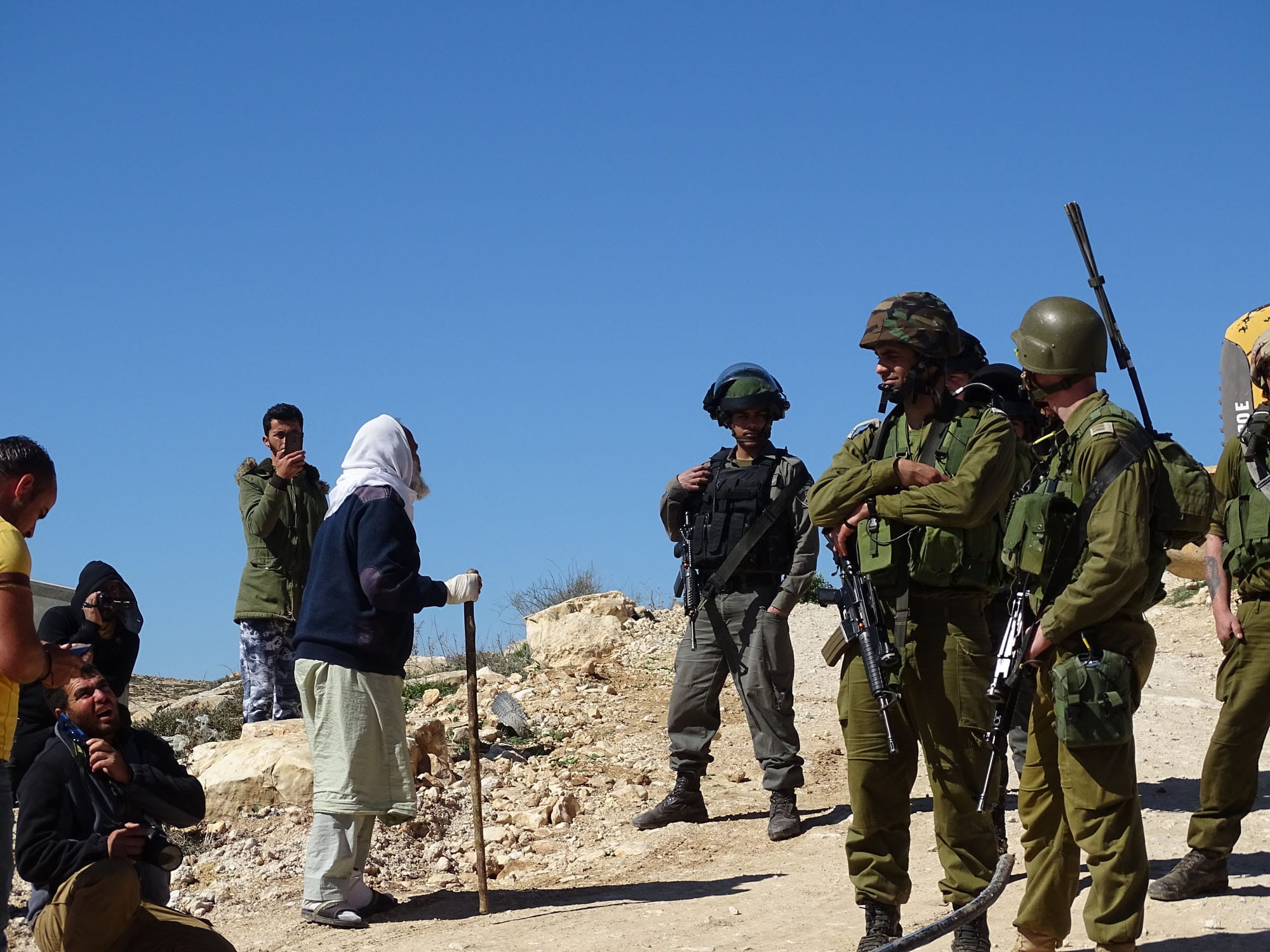 A Palestinian shepherd complains to Israeli soldiers as community water pipes are destroyed