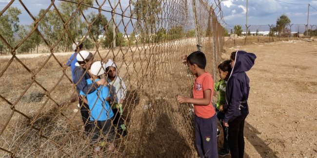 Palestinian children and Israeli settler children try to communicate through the fence