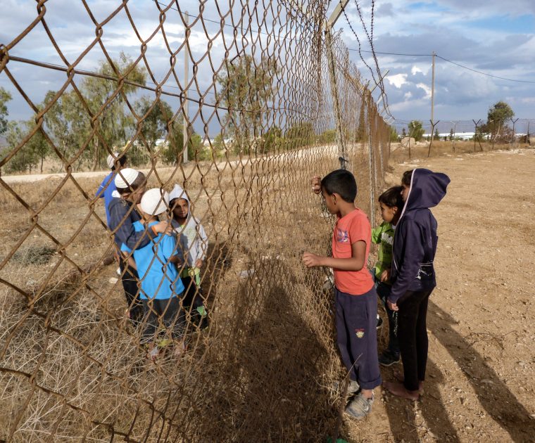 Palestinian children and Israeli settler children try to communicate through the fence