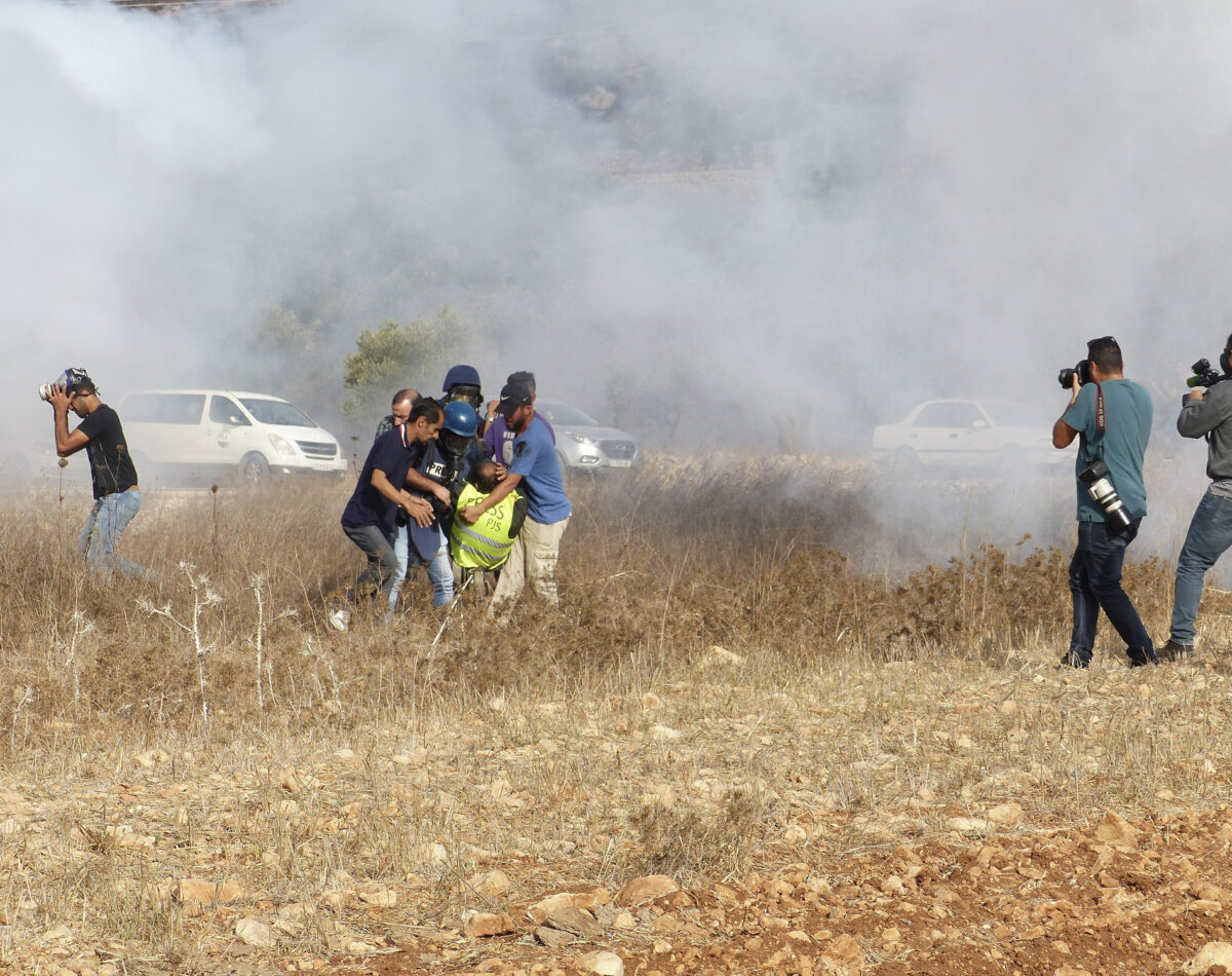 Palestinians run from teargas fired by Israeli soldiers