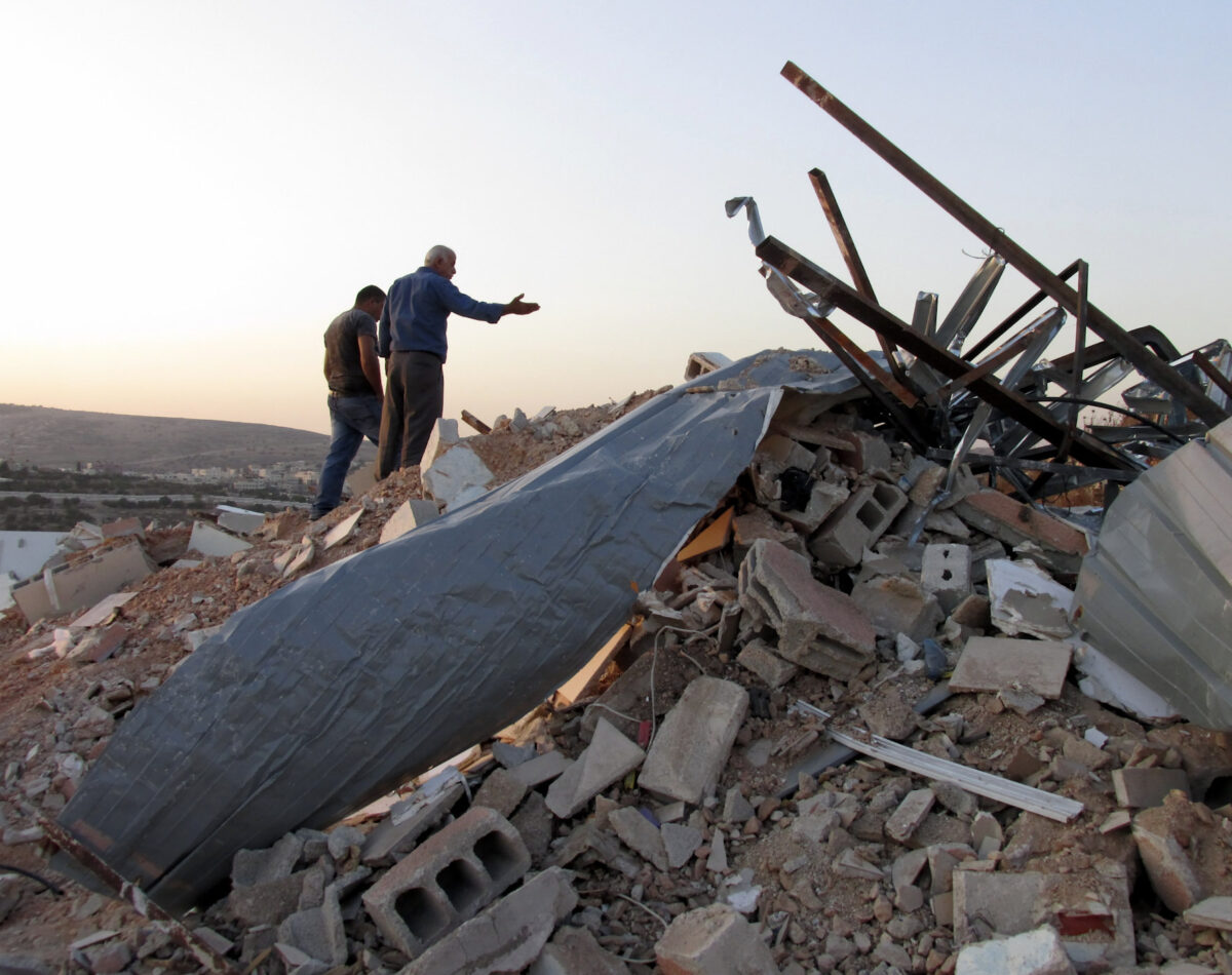 A Palestinian man stands on top of the rubble of his demolished home in East Jerusalem