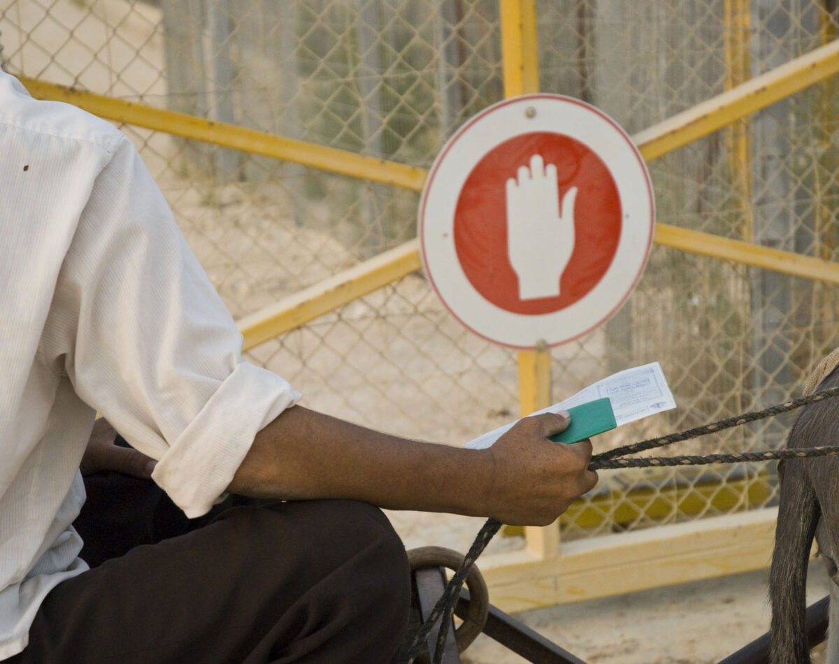 A Palestinian farmer waits with his permit at an agricultural gate to reach his land