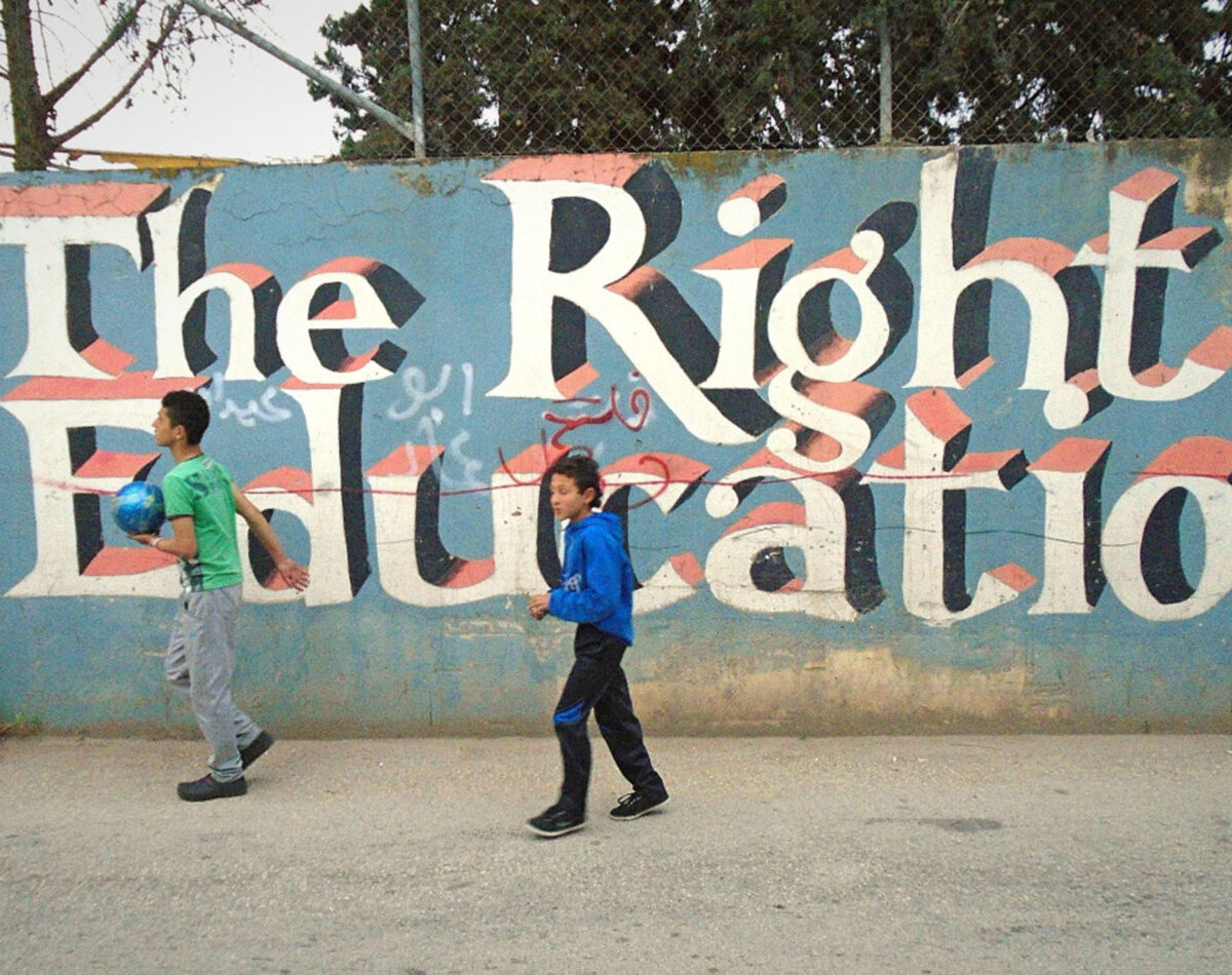 Children play at Aida Refugee Camp in Bethlehem in front of graffiti which reads 'The Right to Education'