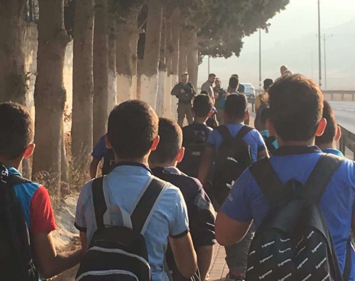 students-approach-the-main-entrance.-teachers-wait-for-them-close-to-armed-soldiers