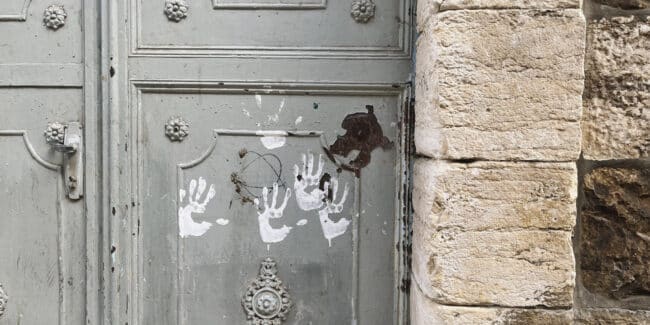 Painted childrens handprints on a doorway in Palestine