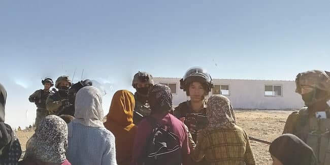 Palestinian women with hijabs facing Israeli soldiers. One solider is a young woman too.